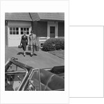 Couple carrying luggage walking towards convertible car in driveway by Anonymous