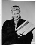 Blond woman smiling wearing winter coat carrying shopping parcel by Anonymous