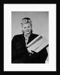 Blond woman smiling wearing winter coat carrying shopping parcel by Anonymous
