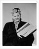 Blond woman smiling wearing winter coat carrying shopping parcel by Anonymous