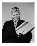 Blond woman smiling wearing winter coat carrying shopping parcel by Anonymous