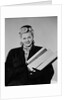 Blond woman smiling wearing winter coat carrying shopping parcel by Anonymous