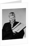 Blond woman smiling wearing winter coat carrying shopping parcel by Anonymous
