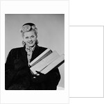 Blond woman smiling wearing winter coat carrying shopping parcel by Anonymous
