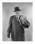 Smiling man carrying shopping boxes wearing hat coat gloves by Anonymous