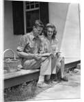 Man woman sitting on porch of farmhouse reading catalog by Anonymous