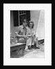 Man woman sitting on porch of farmhouse reading catalog by Anonymous