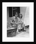 Man woman sitting on porch of farmhouse reading catalog by Anonymous
