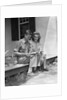 Man woman sitting on porch of farmhouse reading catalog by Anonymous