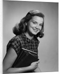 Young smiling woman holding books looking at camera by Anonymous