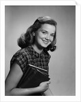 Young smiling woman holding books looking at camera by Anonymous