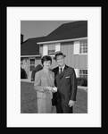 Couple smiling man and woman standing before suburban house by Anonymous