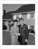 Couple smiling man and woman standing before suburban house by Anonymous