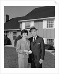 Couple smiling man and woman standing before suburban house by Anonymous