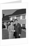 Couple smiling man and woman standing before suburban house by Anonymous