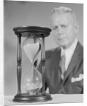 Elderly man soft focus behind hourglass by Anonymous