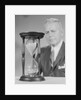 Elderly man soft focus behind hourglass by Anonymous