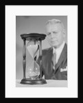 Elderly man soft focus behind hourglass by Anonymous