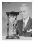 Elderly man soft focus behind hourglass by Anonymous