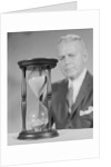 Elderly man soft focus behind hourglass by Anonymous
