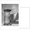 Elderly man soft focus behind hourglass by Anonymous