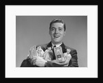 Smiling man holding money bags and bundles of cash by Anonymous