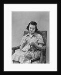 Brunette woman knitting sitting in armchair by Anonymous