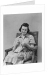 Brunette woman knitting sitting in armchair by Anonymous