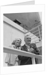 Smiling mature couple at shipboard rail with binoculars by Anonymous