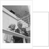 Smiling mature couple at shipboard rail with binoculars by Anonymous