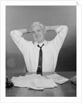Smiling man working on family budget papers at desk by Anonymous