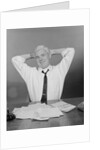 Smiling man working on family budget papers at desk by Anonymous