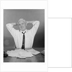 Smiling man working on family budget papers at desk by Anonymous