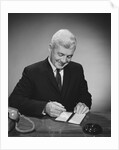 Man writing check from checkbook by Anonymous