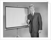 Man standing beside blank screen ready for presentation by Anonymous