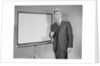 Man standing beside blank screen ready for presentation by Anonymous