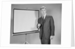 Man standing beside blank screen ready for presentation by Anonymous