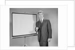 Man standing beside blank screen ready for presentation by Anonymous