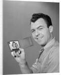 Smiling man holding up wallet with picture of wife and daughter by Anonymous