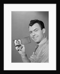 Smiling man holding up wallet with picture of wife and daughter by Anonymous