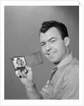 Smiling man holding up wallet with picture of wife and daughter by Anonymous