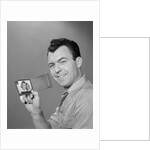 Smiling man holding up wallet with picture of wife and daughter by Anonymous