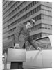 Businessman carrying briefcase getting into car on urban street by Anonymous