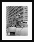 Businessman carrying briefcase getting into car on urban street by Anonymous