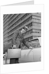 Businessman carrying briefcase getting into car on urban street by Anonymous