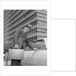 Businessman carrying briefcase getting into car on urban street by Anonymous