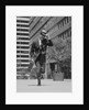 Businessman carrying briefcase holding his hat on running down urban sidewalk by Anonymous