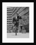 Businessman carrying briefcase holding his hat on running down urban sidewalk by Anonymous