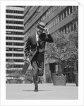 Businessman carrying briefcase holding his hat on running down urban sidewalk by Anonymous