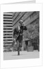 Businessman carrying briefcase holding his hat on running down urban sidewalk by Anonymous